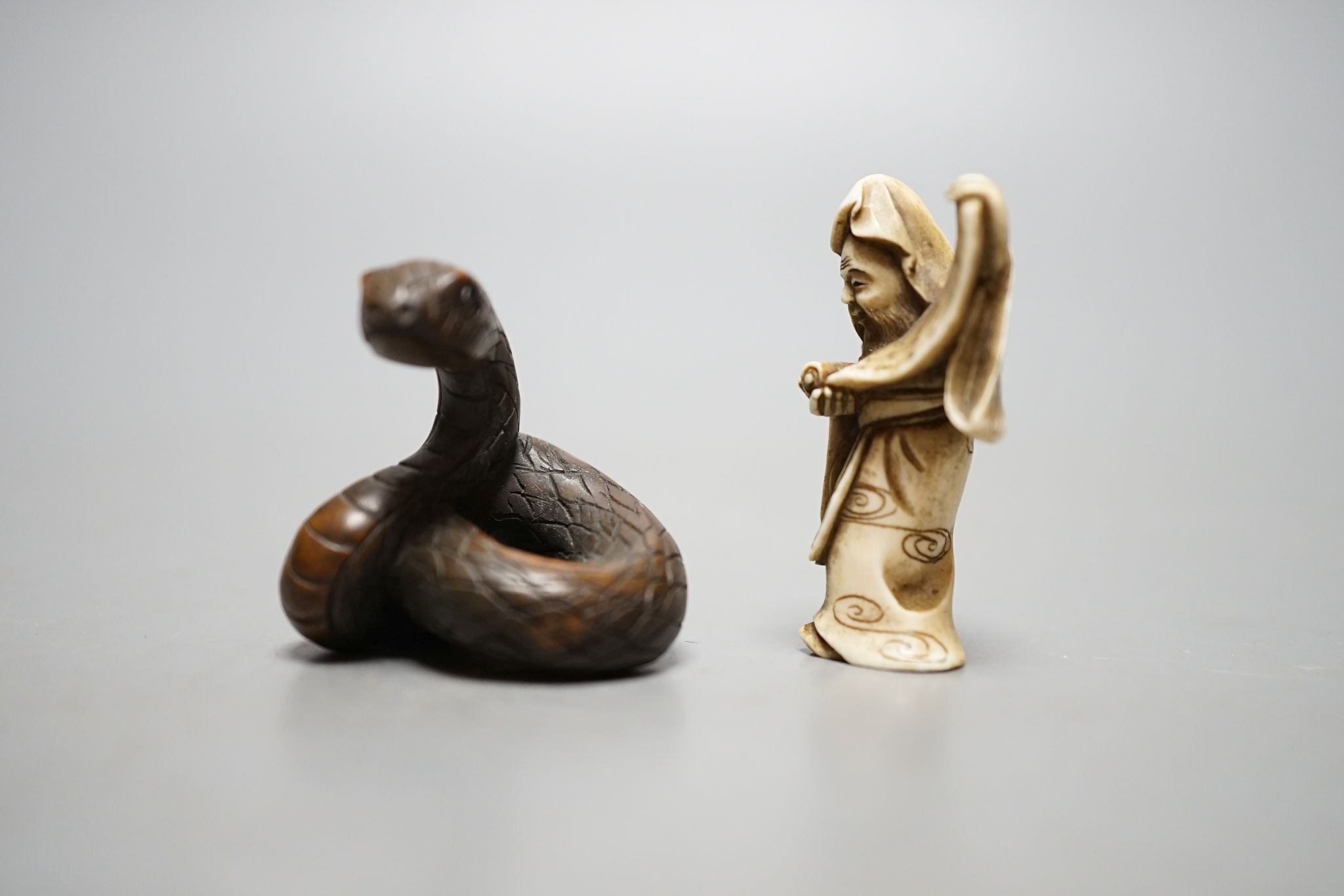 A Japanese ivory figure of a sage and a signed carved wood snake netsuke, 5cm long